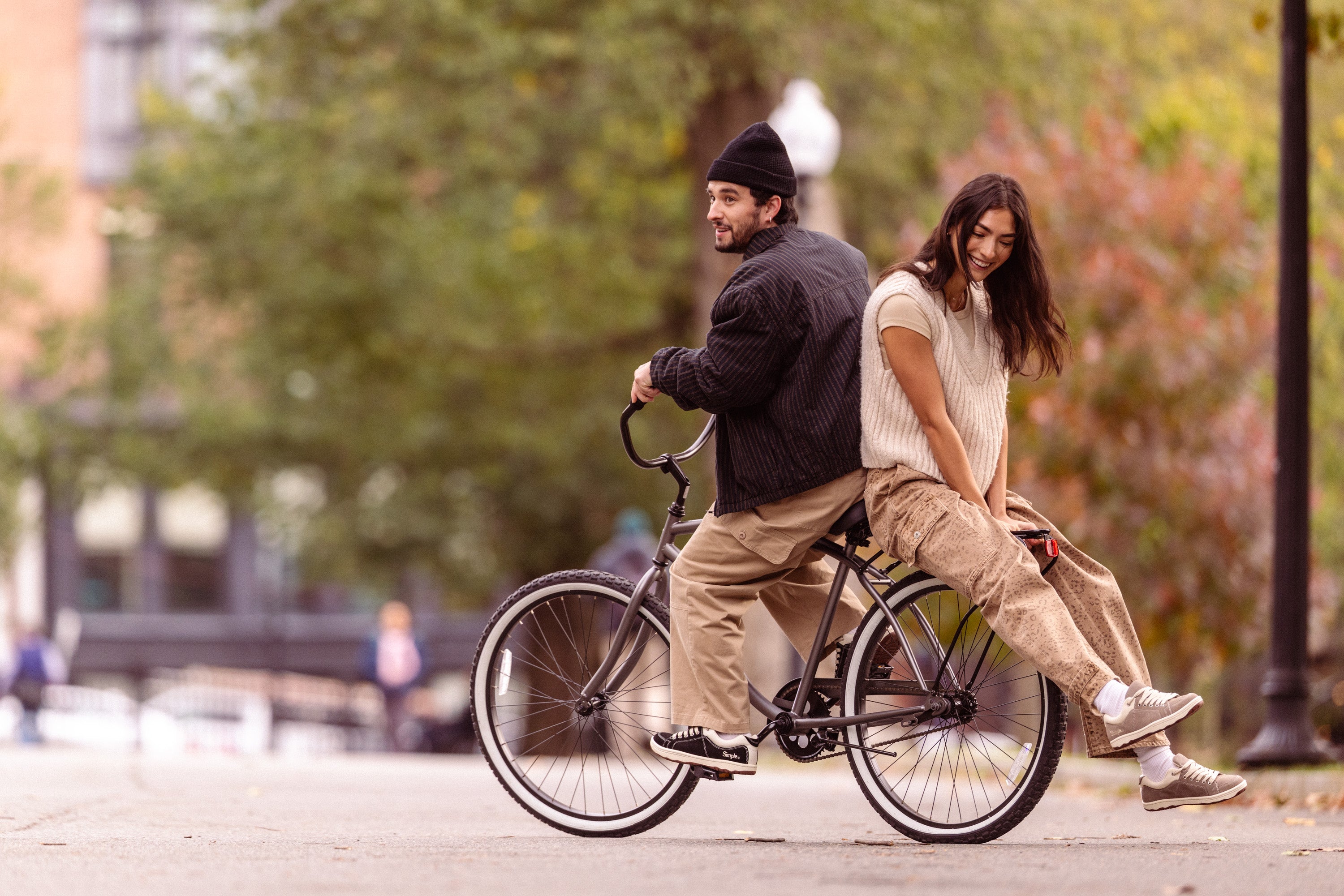 Two people riding a bicycle together on a city street.