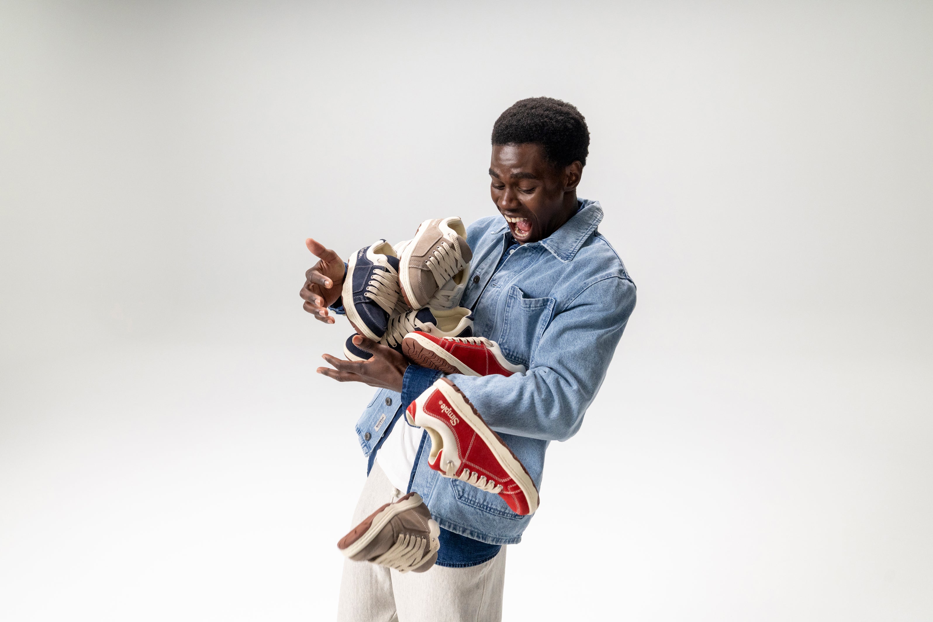 Person holding and showing off a pair of sneakers against a plain background