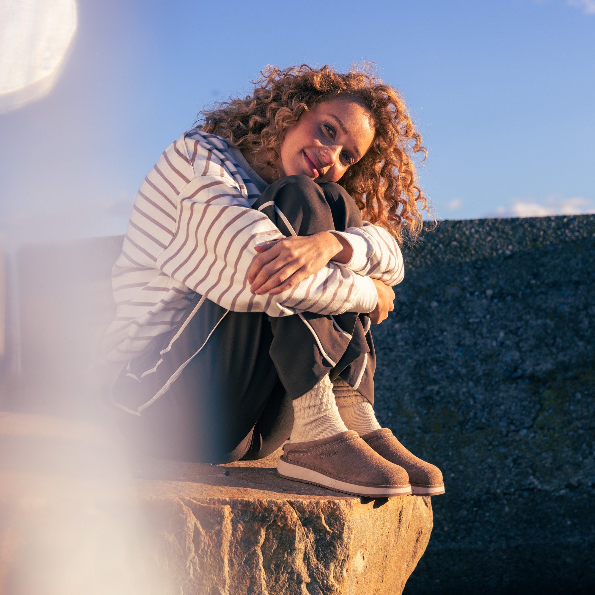 Woman sitting on a stone ledge with a scenic background