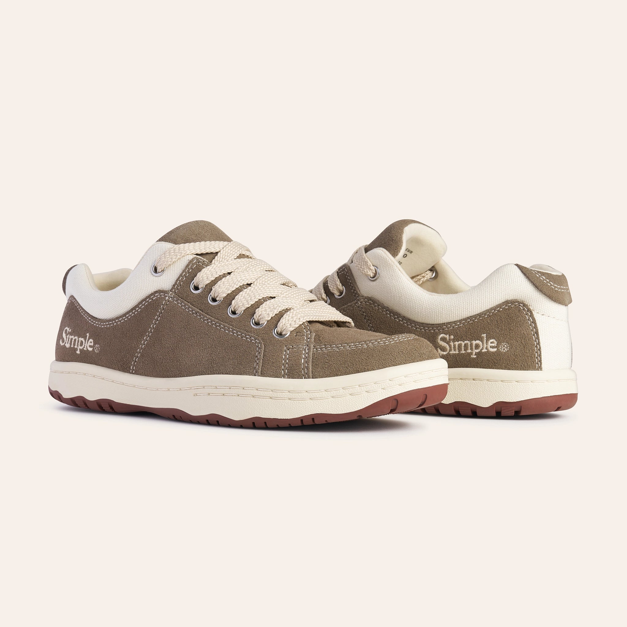 Brown suede sneakers with cream accents, featuring lace-up design and durable rubber soles.