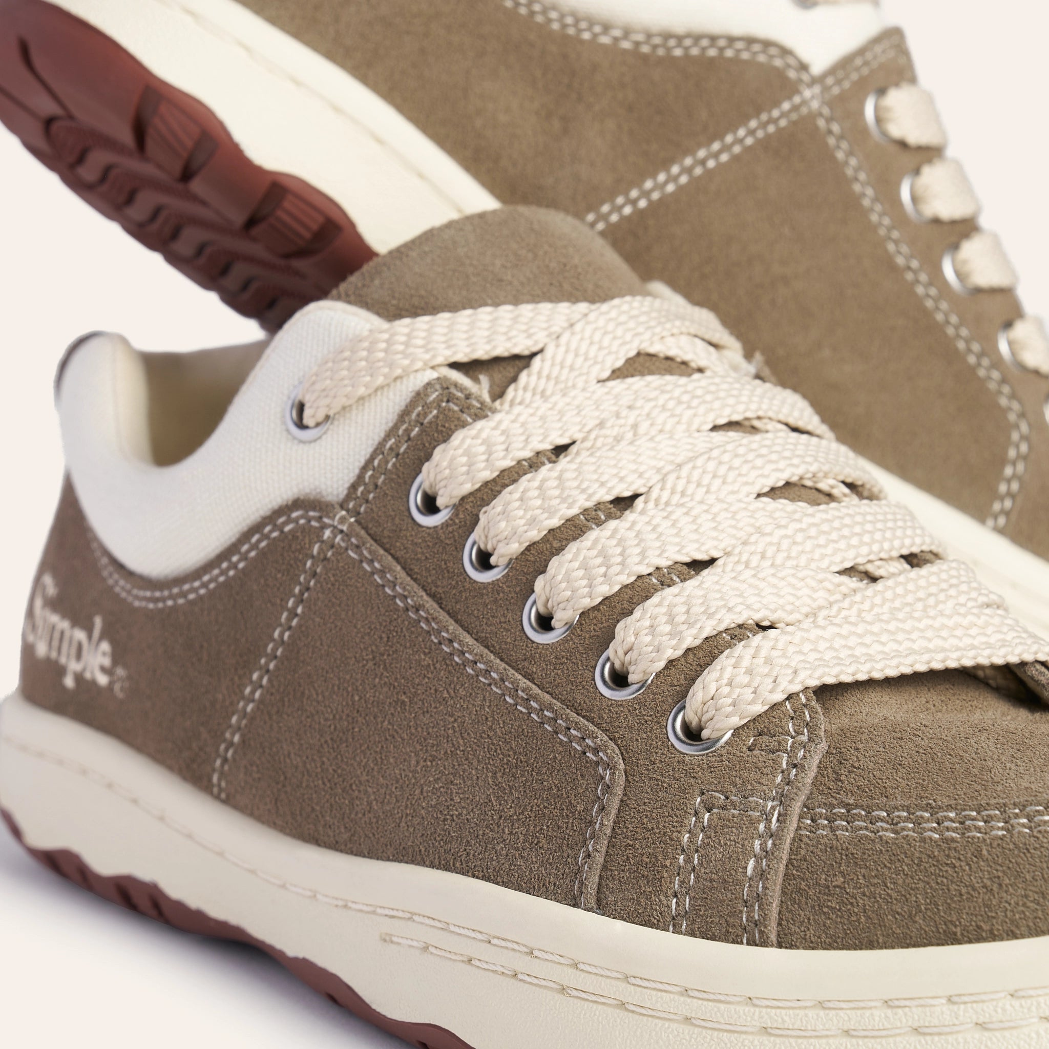 Stylish brown suede sneakers with cream laces and rubber sole, perfect for casual wear.