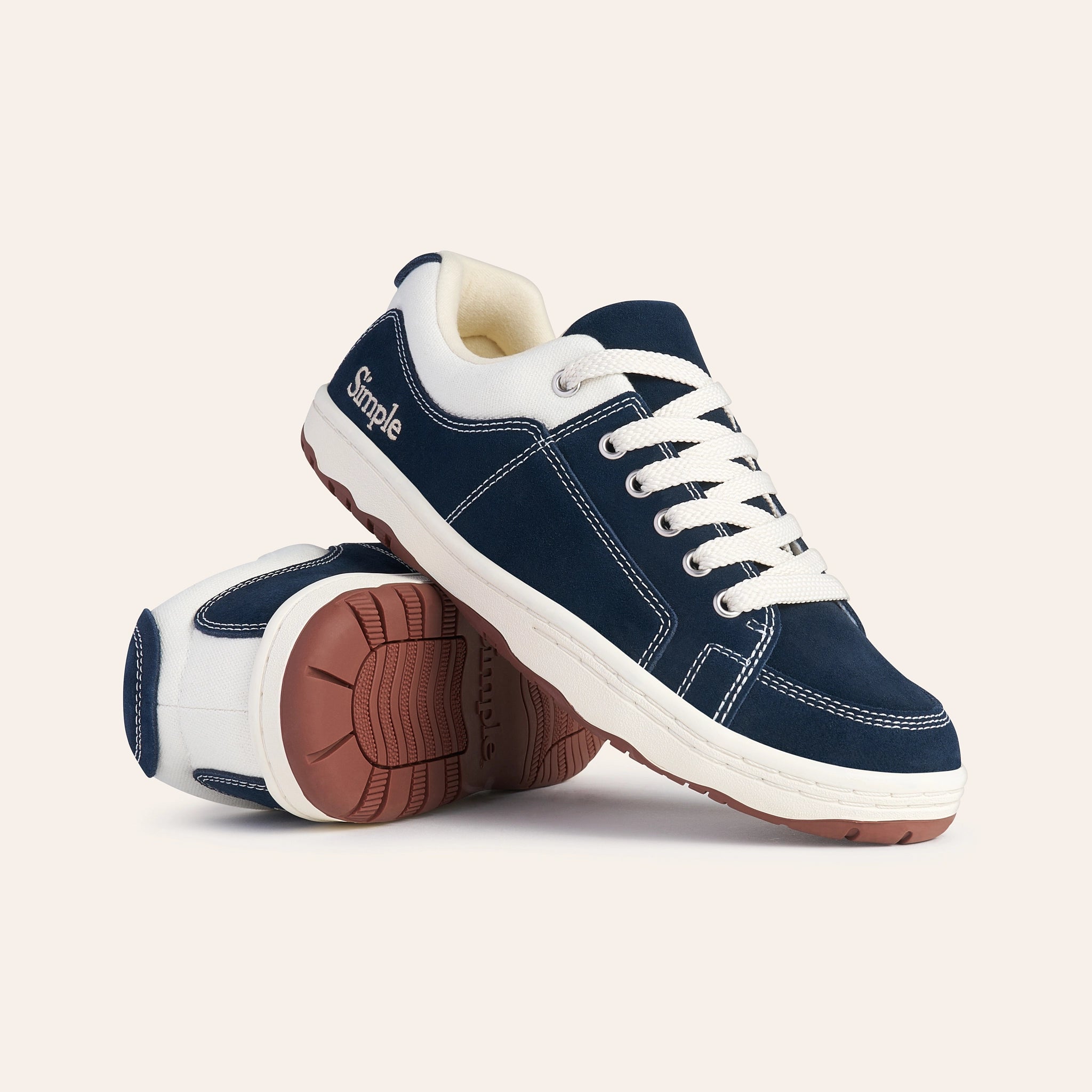 Navy blue sneakers made of suede with white laces and rubber soles, featuring a casual design by Simple.
