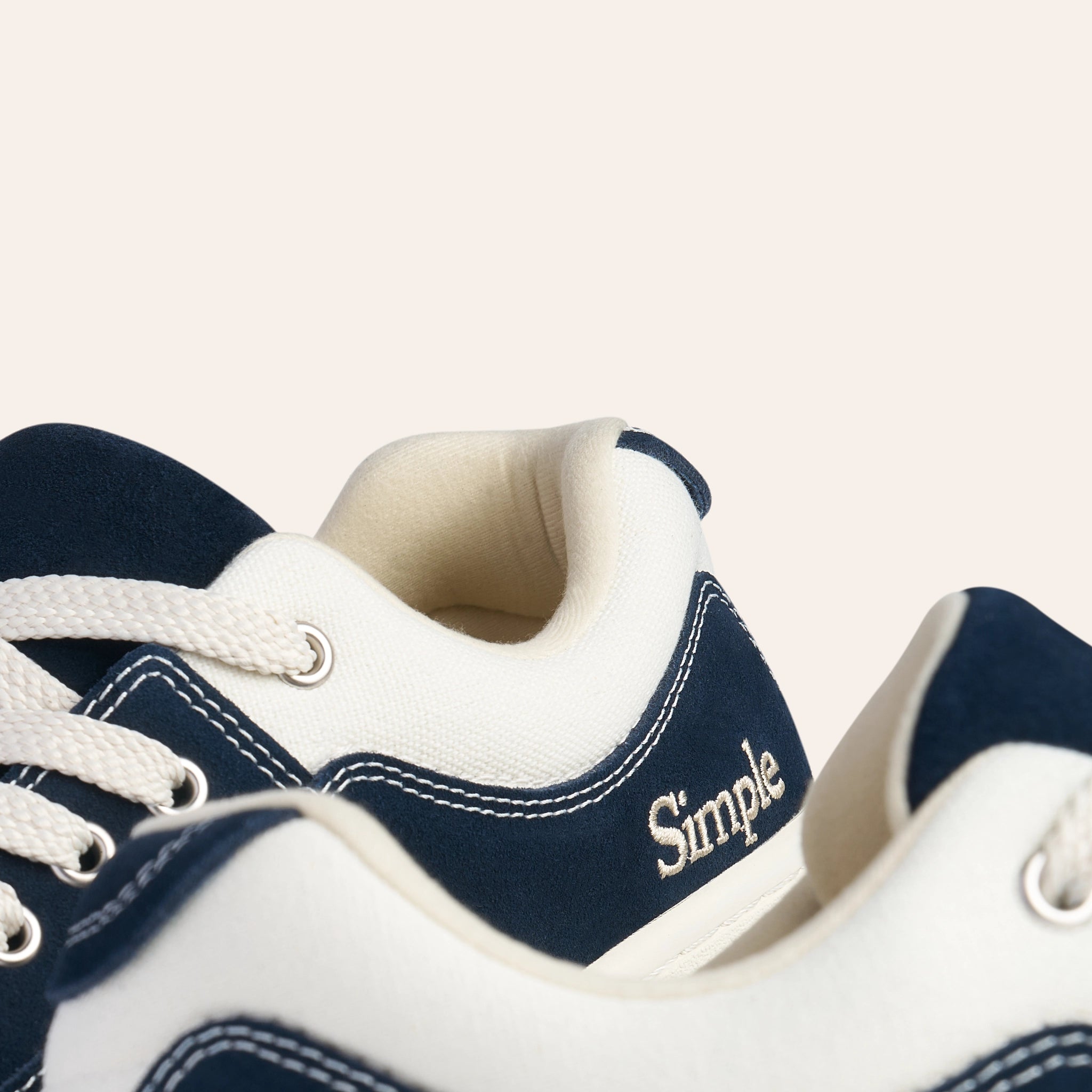 Navy blue suede sneakers with white accents and laces, featuring Simple branding for casual style.