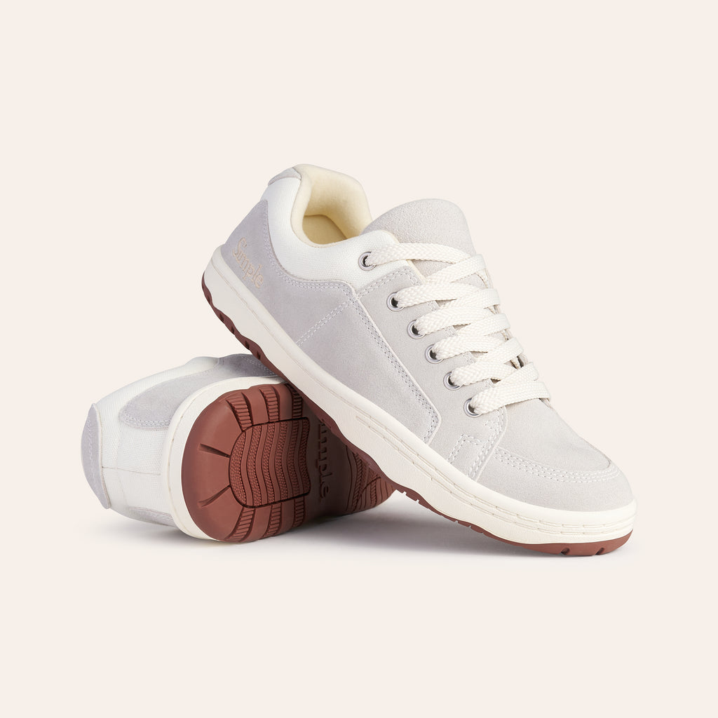 Light gray suede sneakers with white laces and brown rubber sole, featuring a minimalist design.