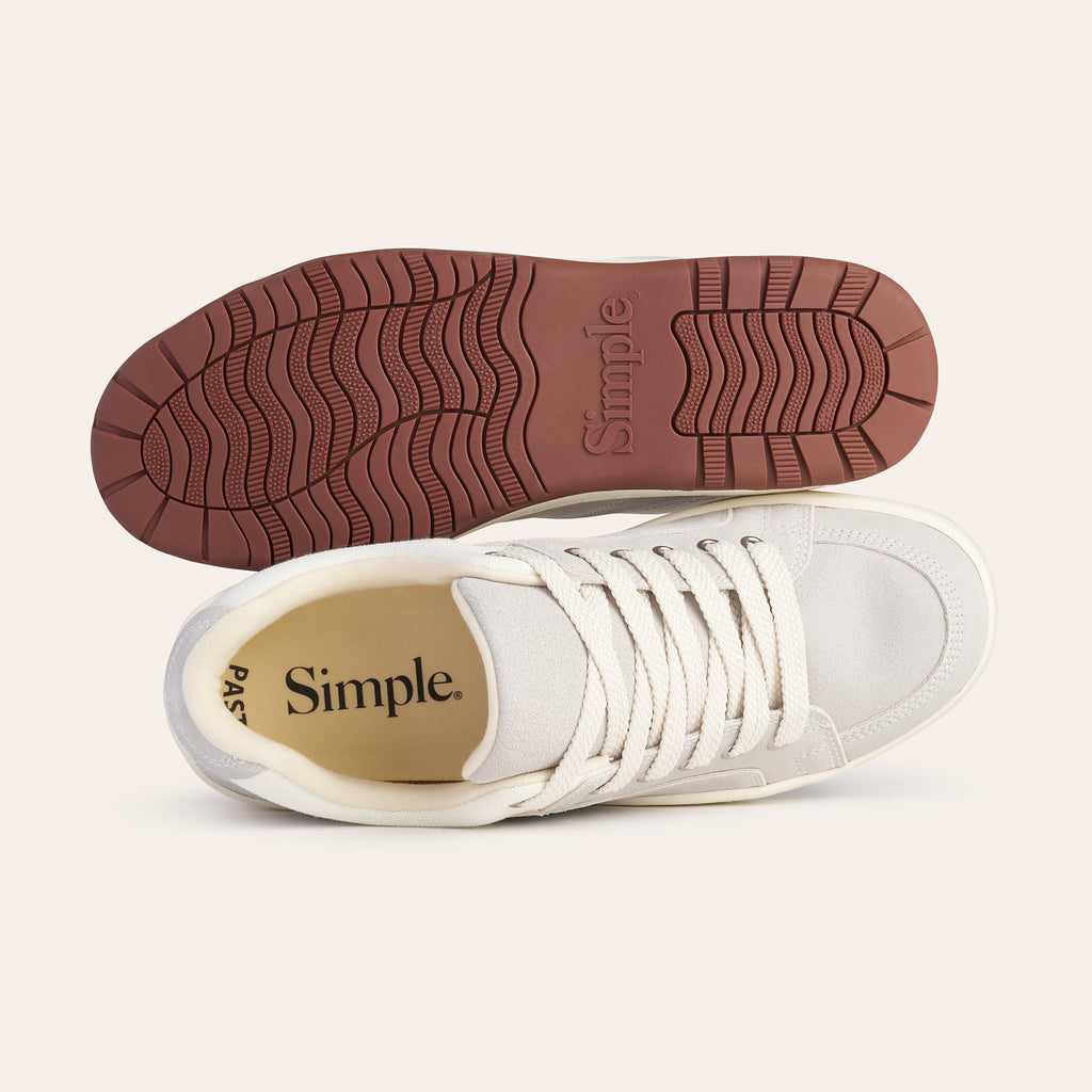 Simple white sneakers with a rubber sole, lace-up design, and textured outsole for grip.