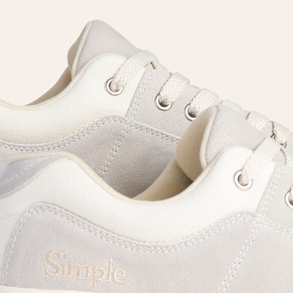 Light grey suede sneakers with cream canvas accents and lace-up closure, featuring a Simple logo.