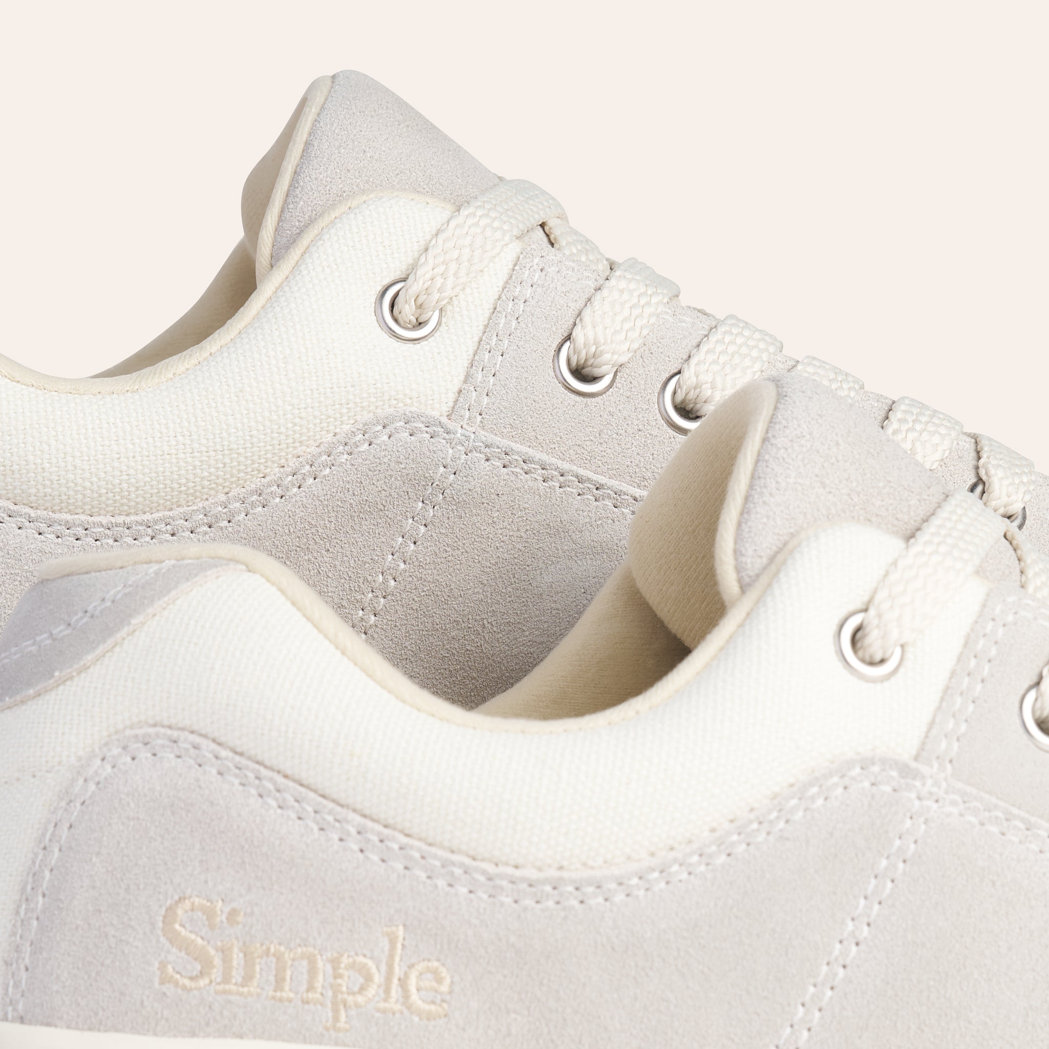Light grey suede sneakers with cream canvas accents and lace-up closure, featuring a Simple logo.