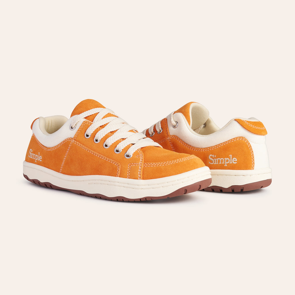Casual orange suede sneakers with white accents and laces for comfortable everyday wear.