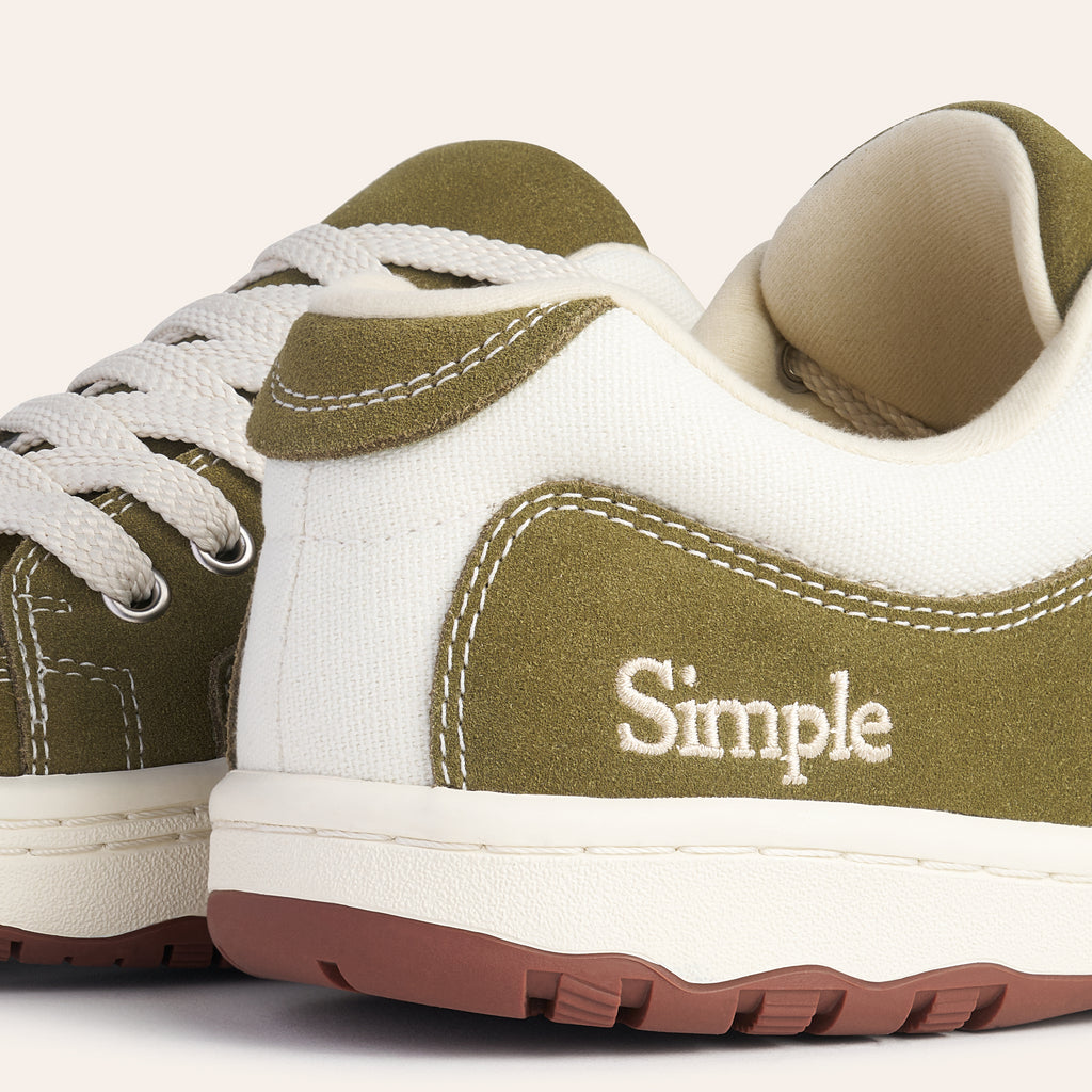 Simple brand sneakers in olive green and white canvas with rubber sole and lace-up design.