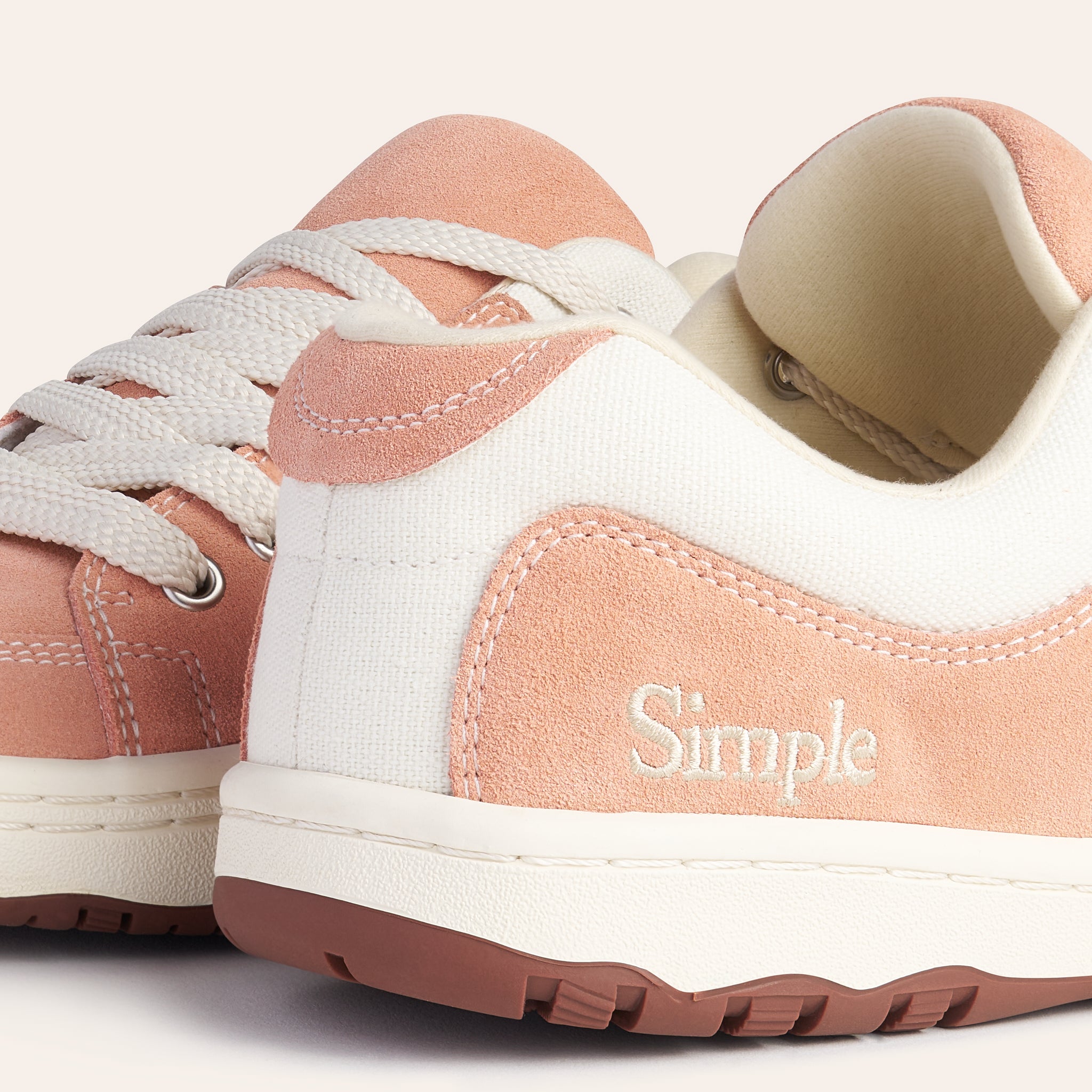 Casual pink and white suede shoes with lace-up design and cushioned insole for comfort.